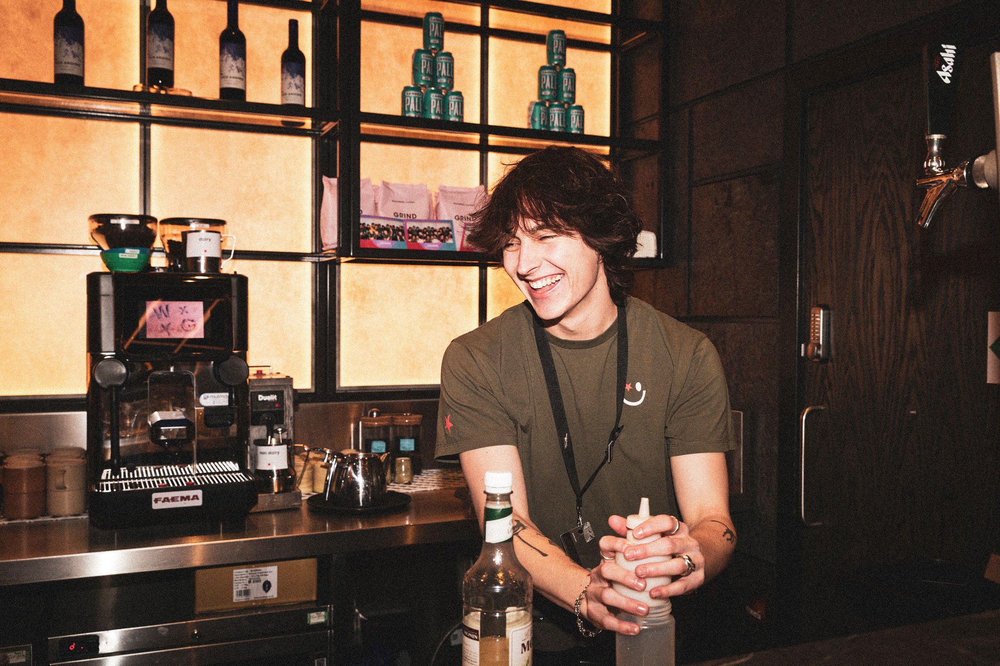 Man preparing a drink at a bar, smiling.