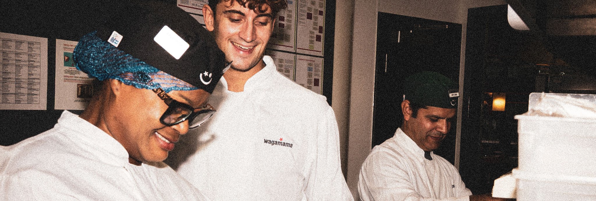 Three chefs smiling at work in the kitchen.