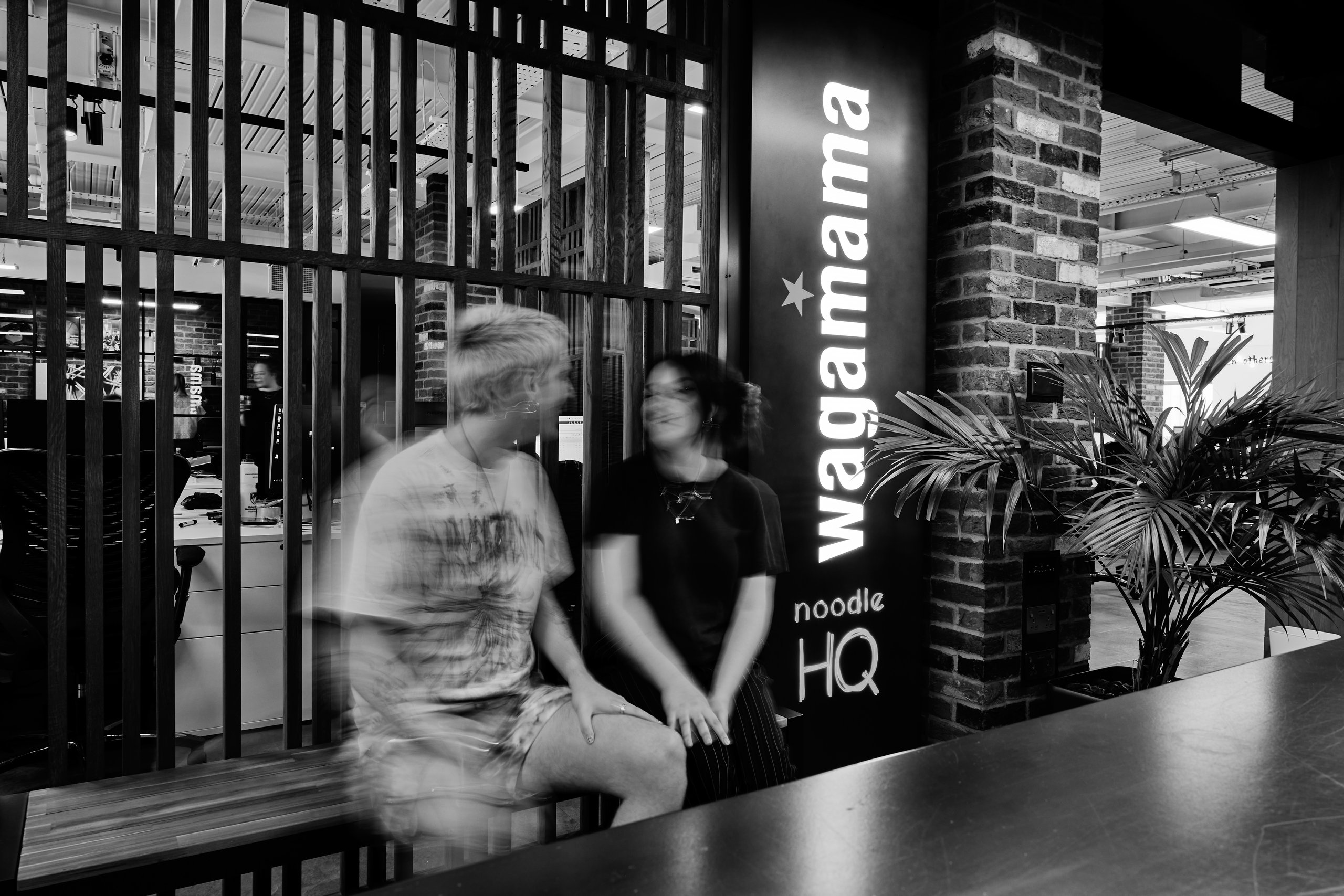 Blurred figures, Wagamama sign, and wooden slatted wall.