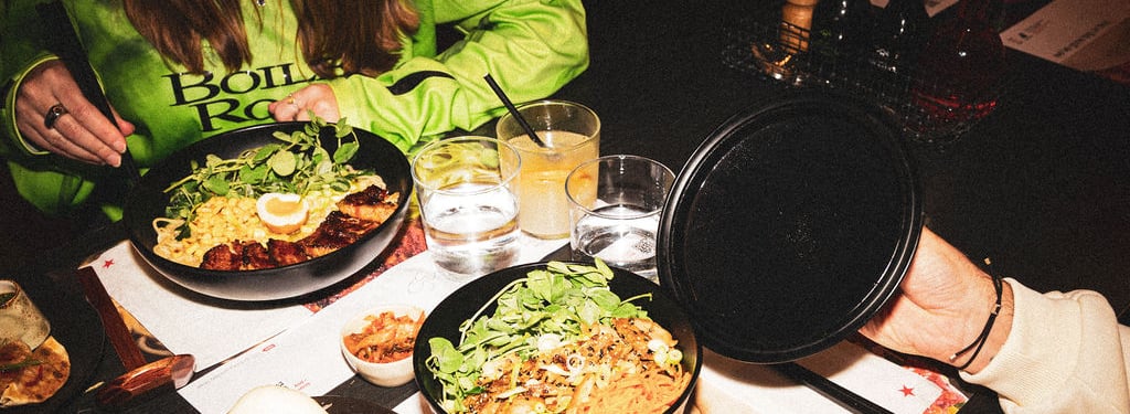 A table spread with ramen, bao buns, and gyoza at a restaurant setting.