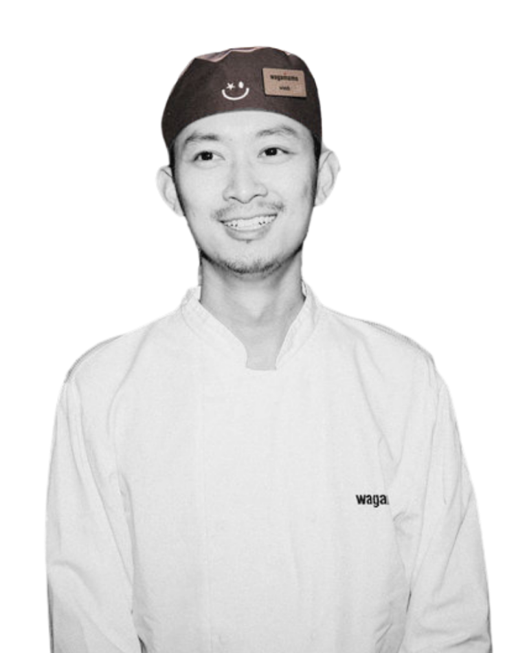 A smiling chef wearing a Wagamama uniform and a branded skull cap against a white background.