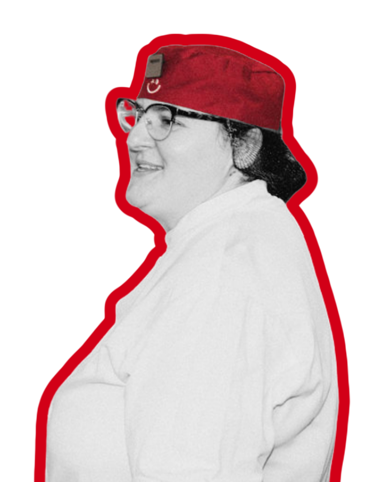 A woman wearing a red cap with a smiley face logo, viewed in profile against a plain background.