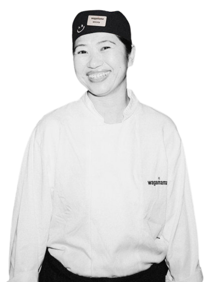 A smiling Wagamama chef wearing a uniform and cap against a plain white background.