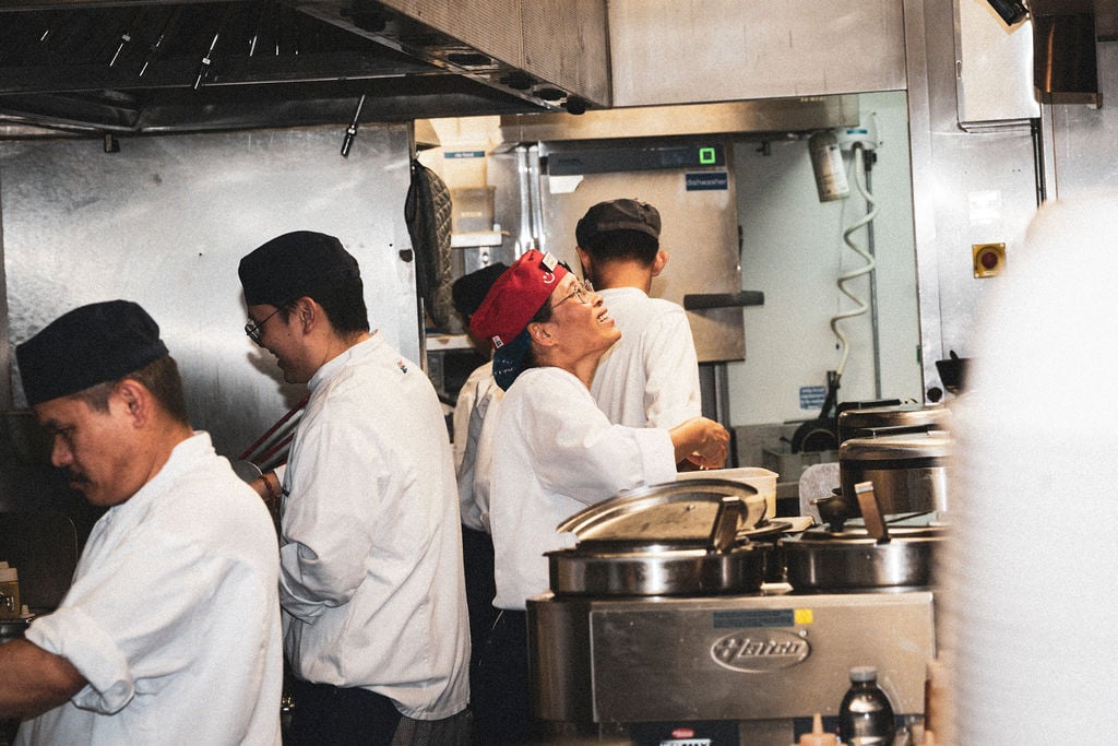 A group of professional chefs working in a commercial restaurant kitchen wearing uniforms.